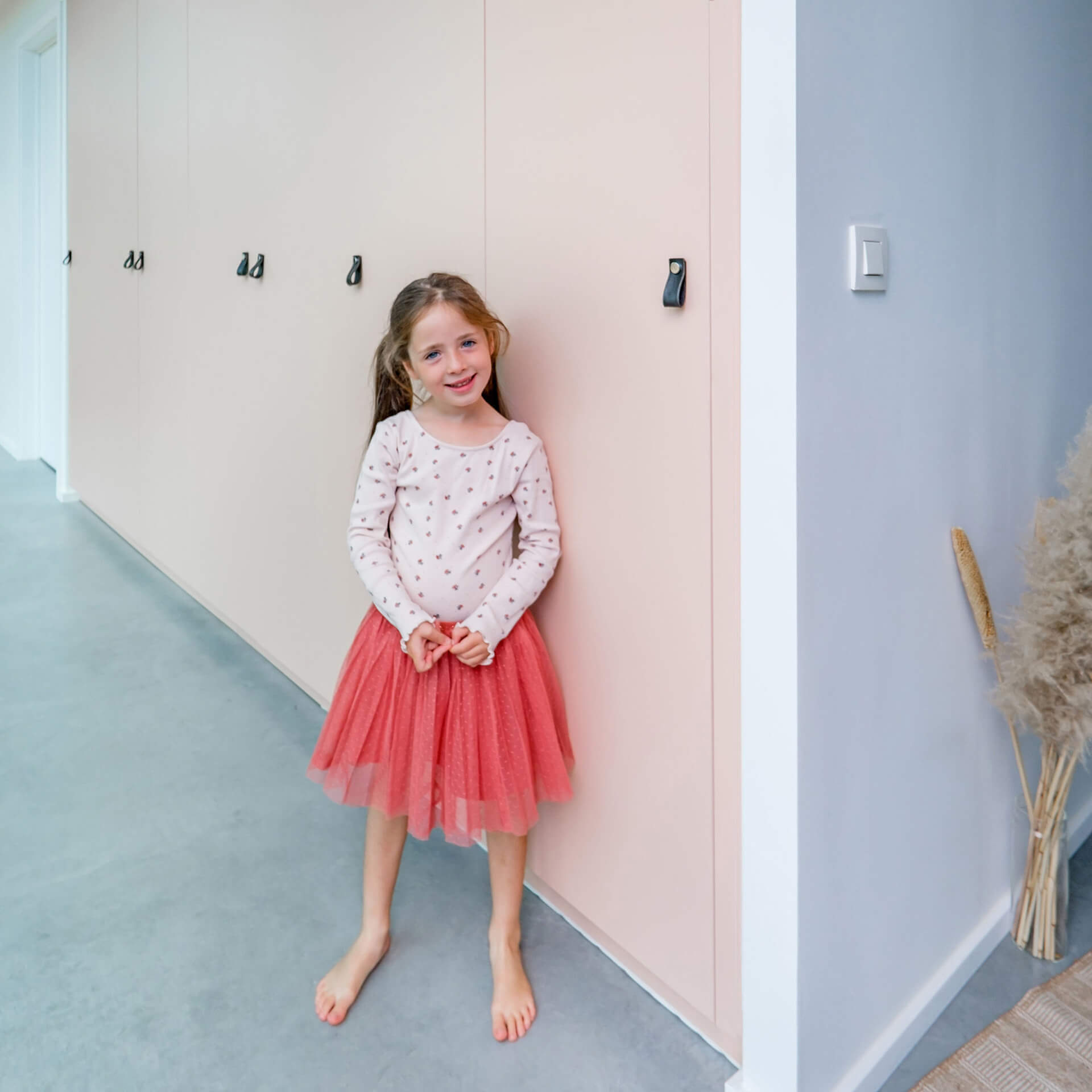 a young girl standing in front of a made to measure cabinet from maatkasten online