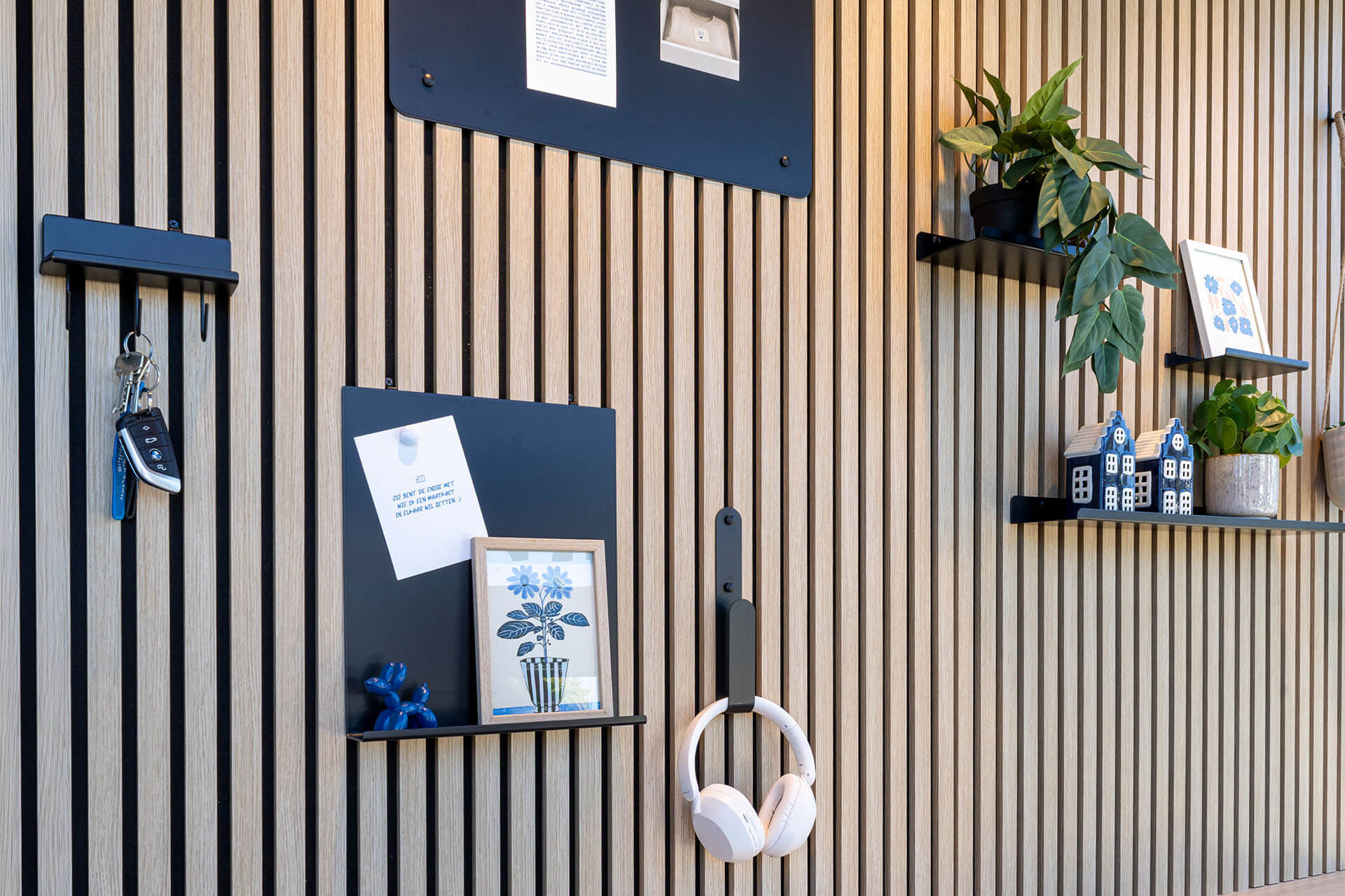 A wall covered with acoustic panels and accessories such as a magnetic board, wall shelves, and handy hooks. 