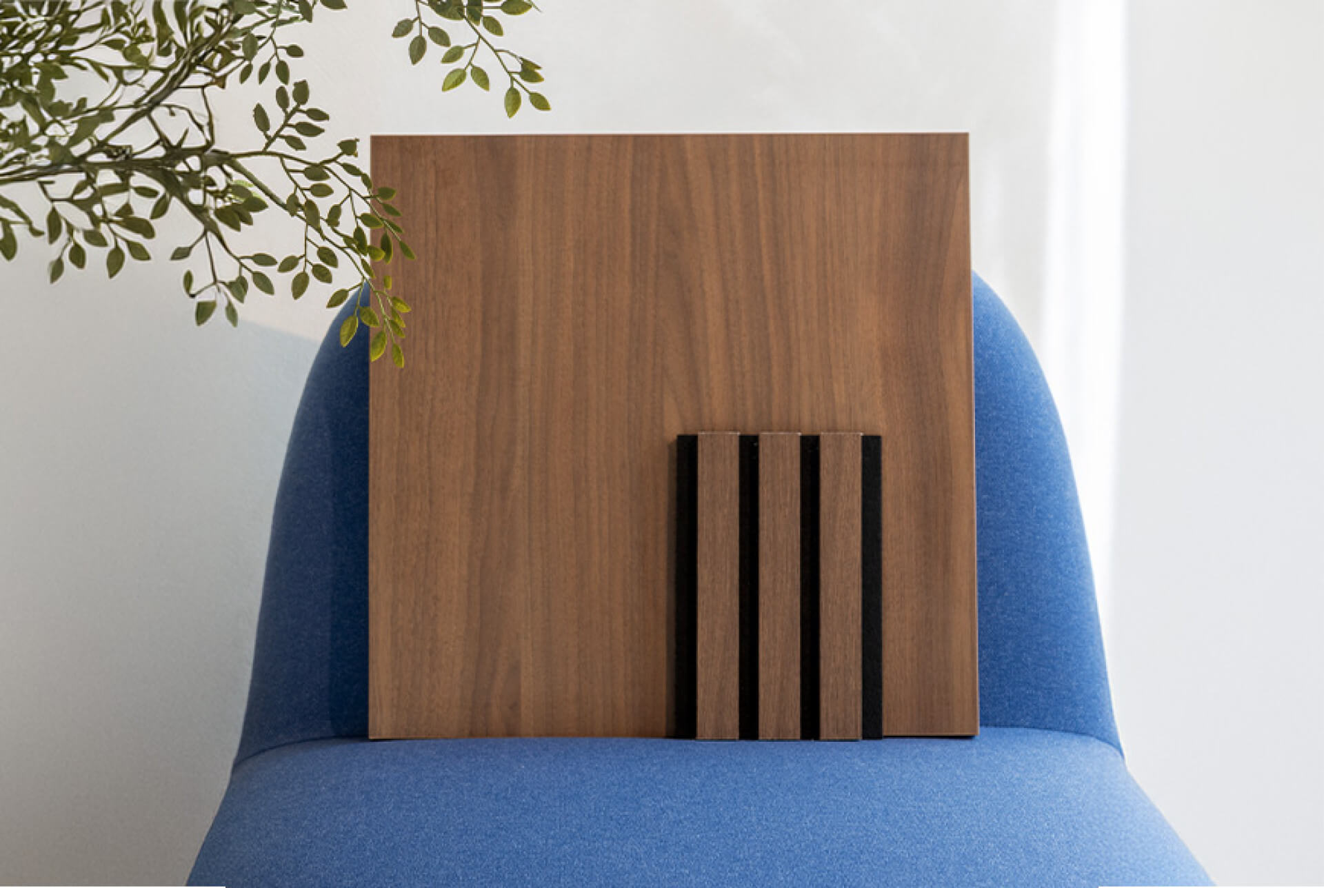 Staal van een Walnut Oak akoestisch wandpaneel op een blauwe stoel
