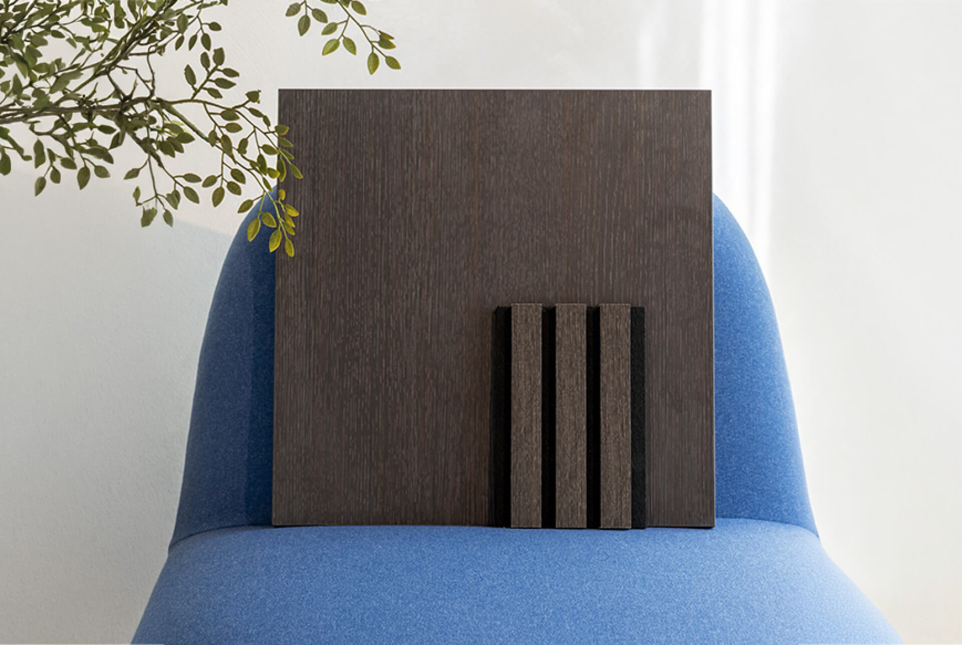 Staal van een Smoked Oak akoestisch wandpaneel op een blauwe stoel