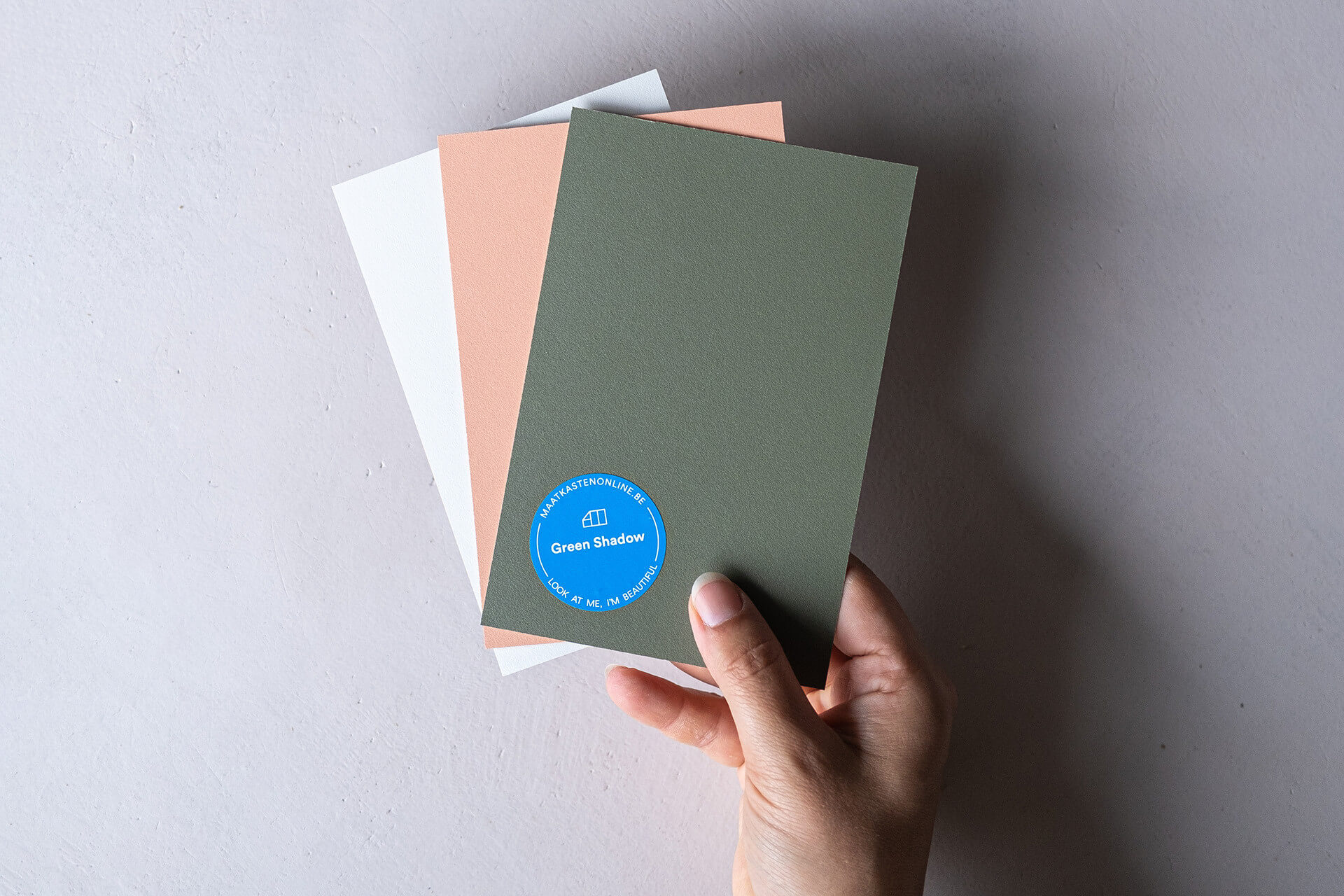 Une main avec trois échantillons de couleurs pour une armoire sur mesure, des armoires sur mesure en ligne 