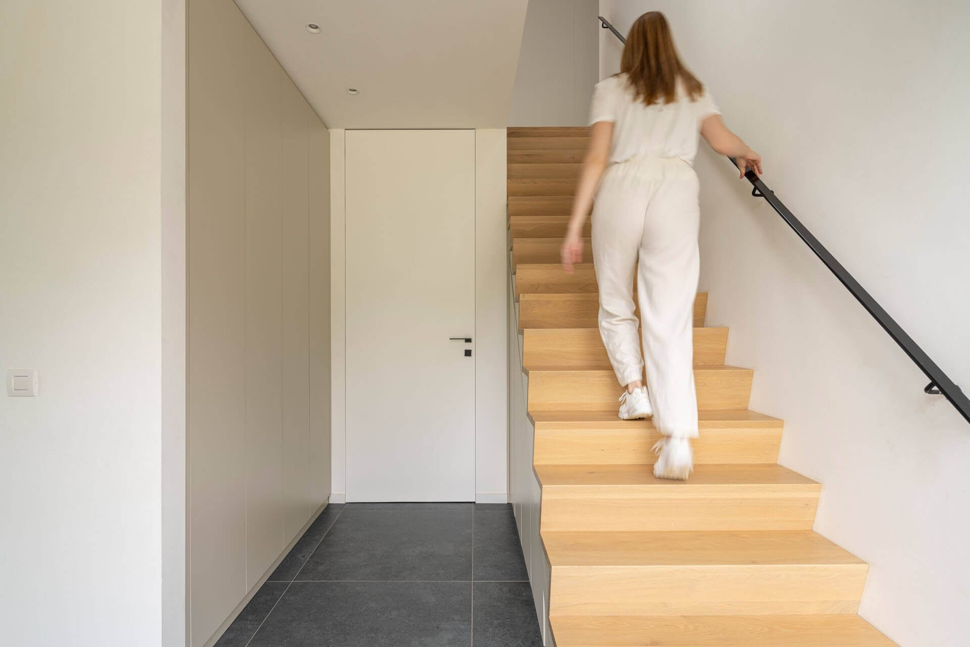 Dame loopt de trap op in hal met trapkast op maat