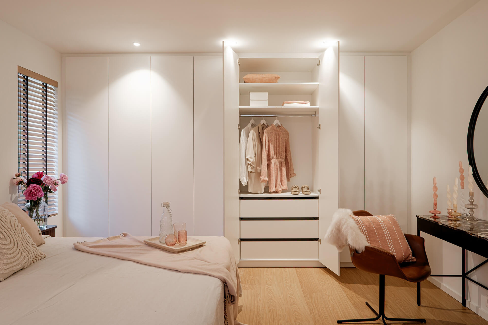 Ingebouwde witte kledingkast op maat in een sfeervolle slaapkamer met roze styling