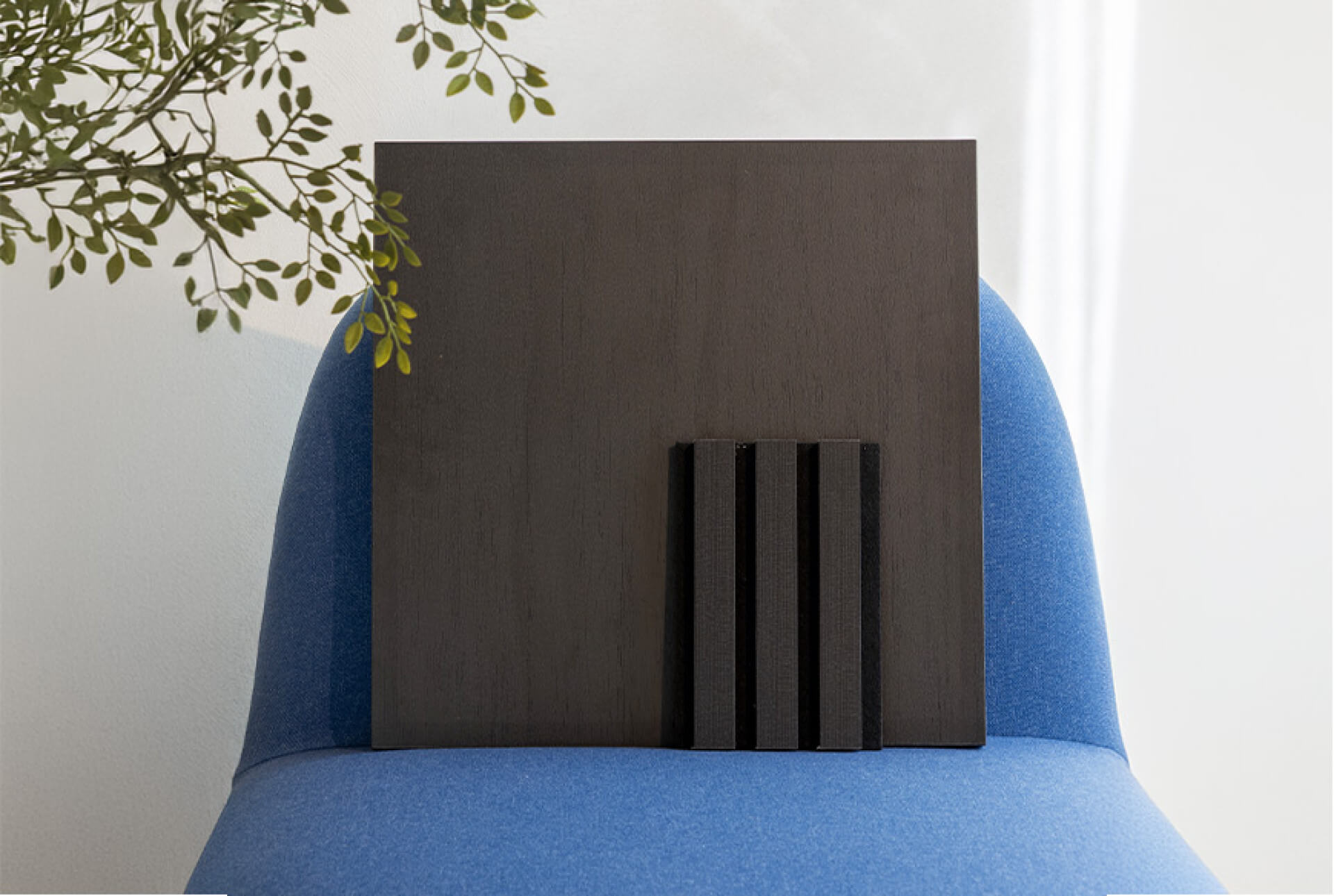 Staal van een Charcoal Oak akoestisch wandpaneel op een blauwe stoel