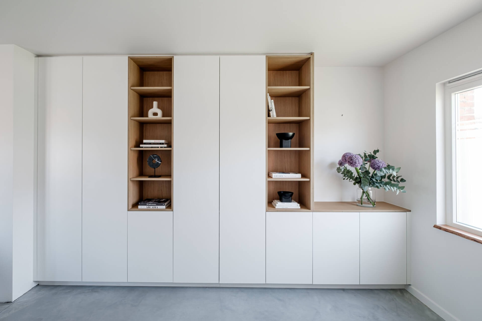Witte wandkast op maat met twee open niskasten in houtstructuur en een lage kast met bovenblad