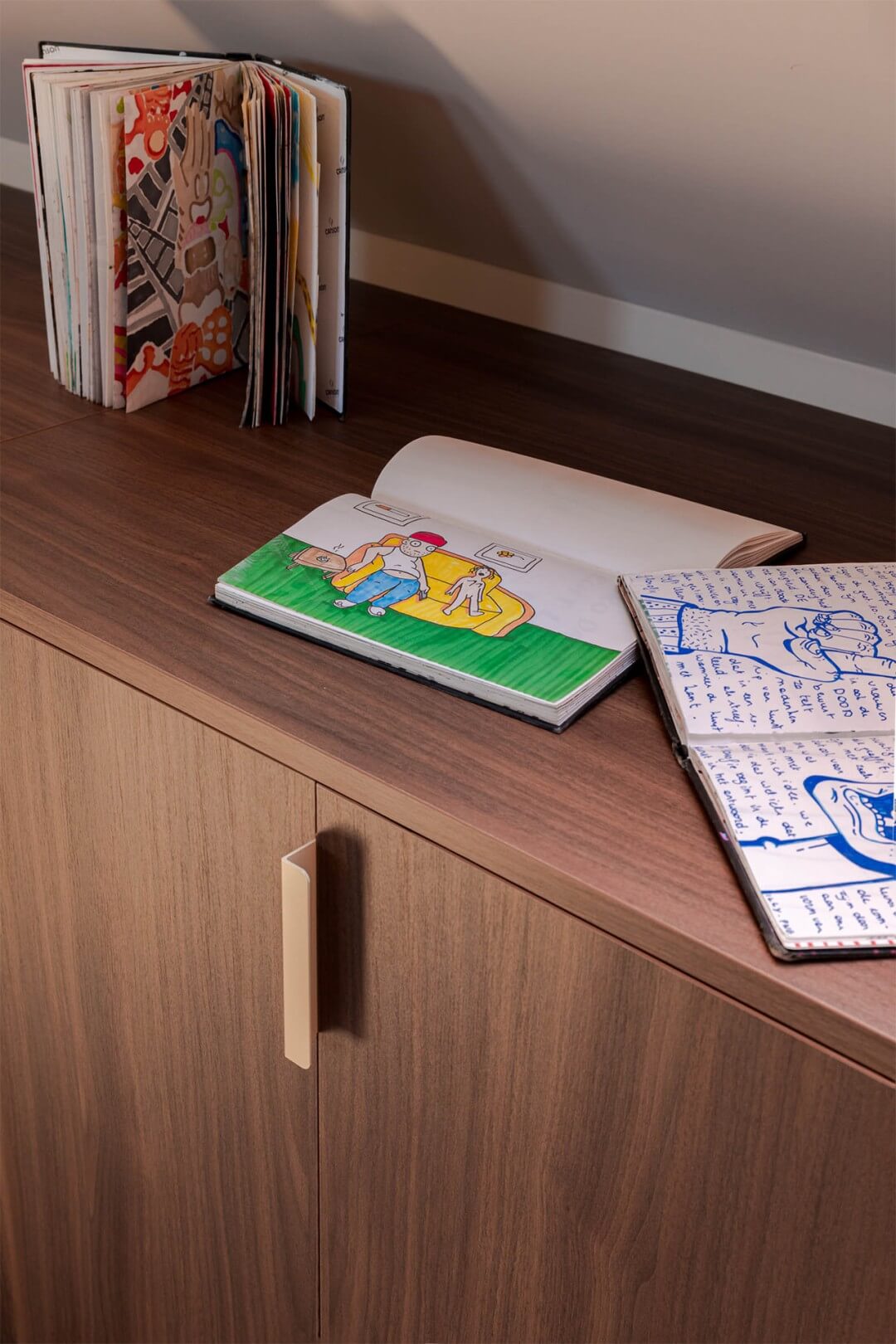 VTM programma Huis Gemaakt deelnemers Wielsbeke detailshot kwaliteit extra kamer zolderkamer met dressoir op maat in Lorenzo Walnut en Tonton handgreep met tekenboek bovenop dressoirkast