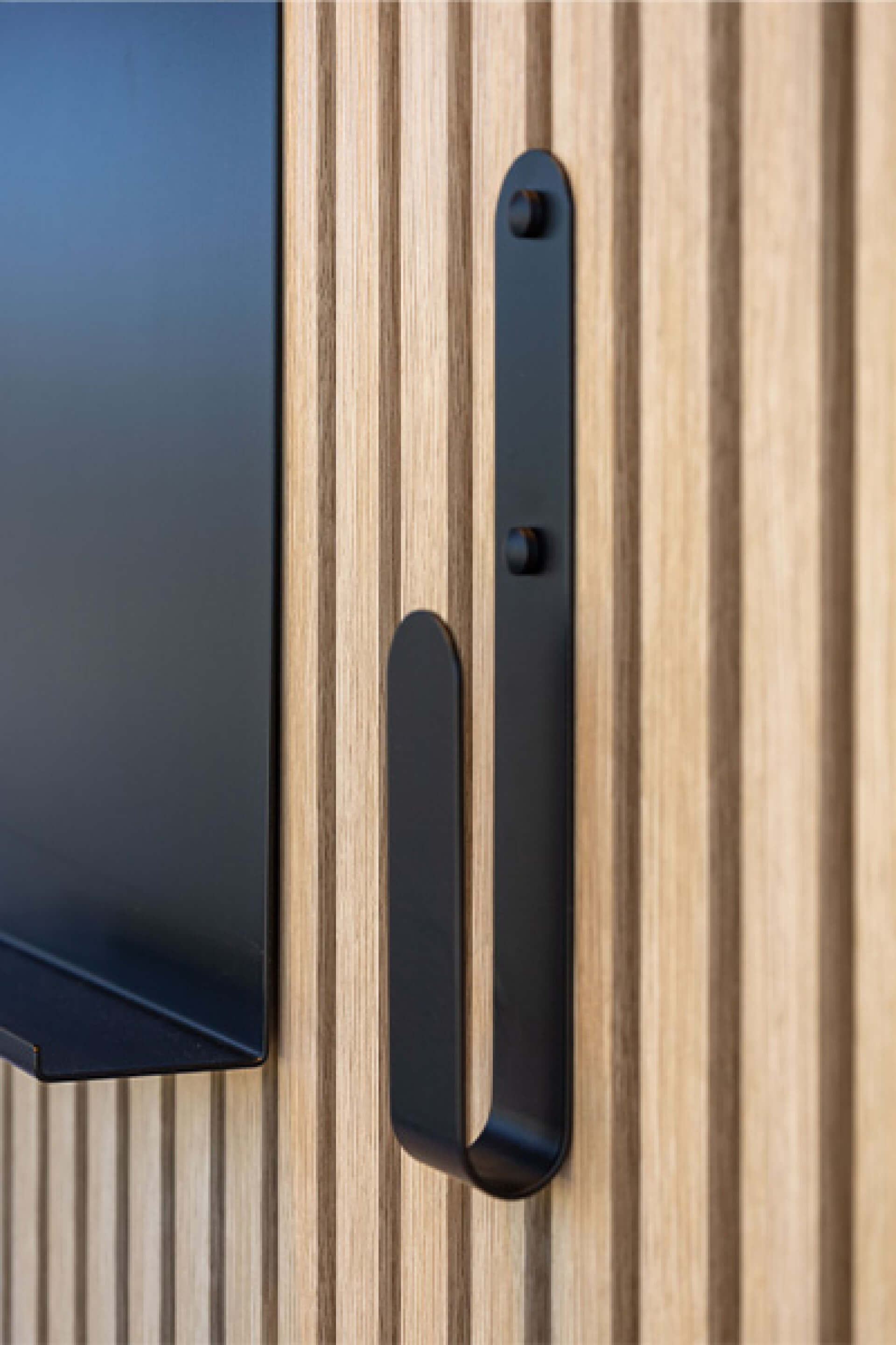 Rechter zijaanzicht design haak op een akoestisch wandpaneel met andere wandpaneelaccessoires in beeld. Verkrijgbaar in de Maatkasten Online boetiek.