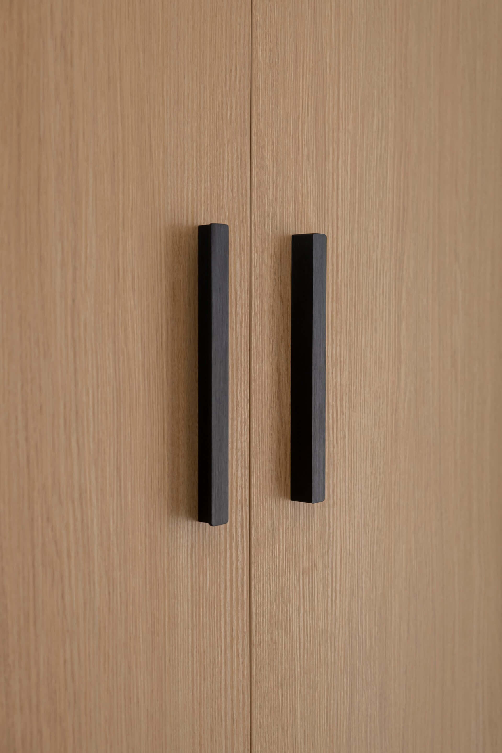 Detail shot van Bar handgrepen in het zwart op een maatkast in Essential Oak Naturel.