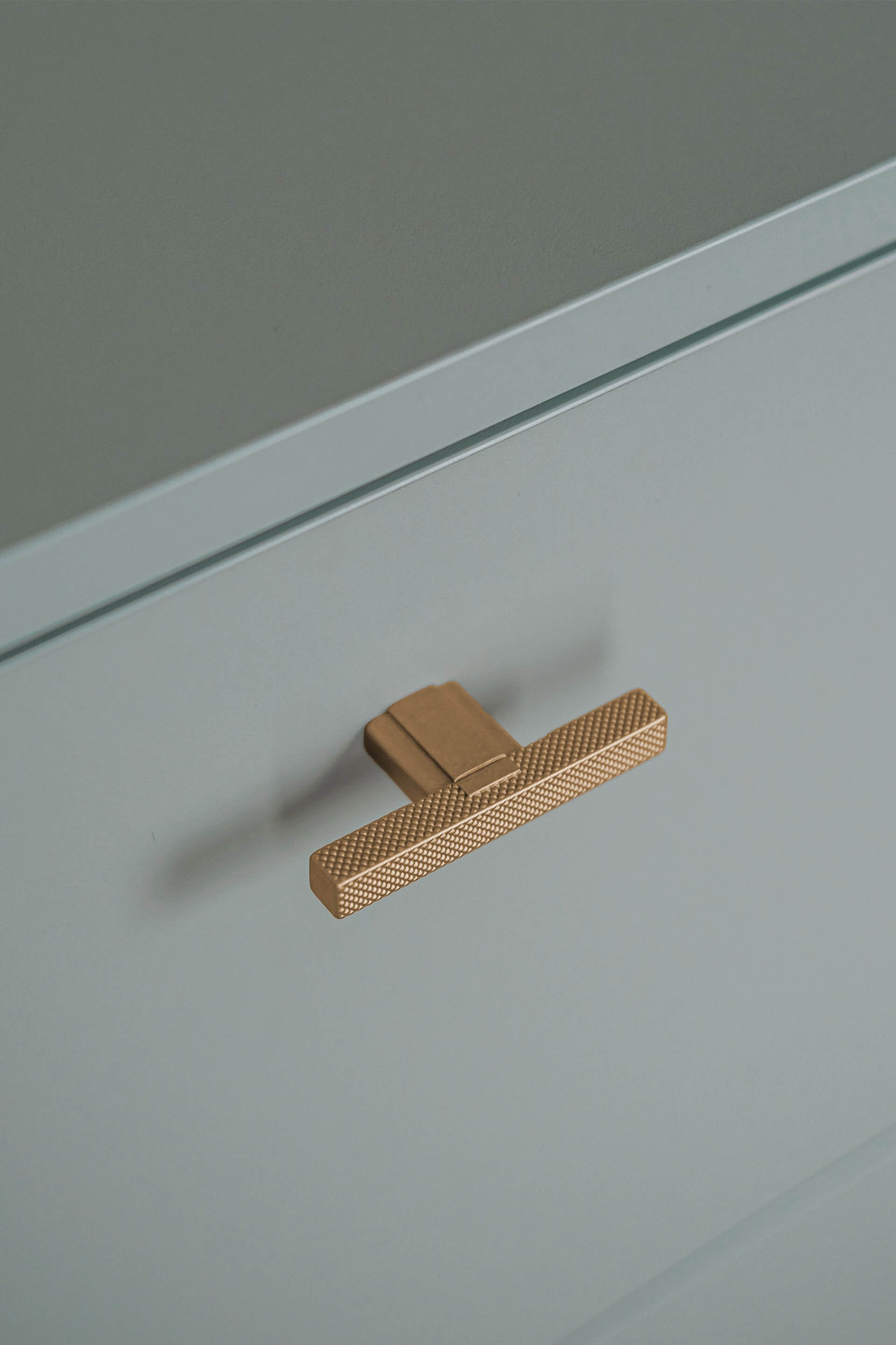 Detail shot van de T-Diamond handgrepen in Messing op een op maat gemaakte opbergkast in Industrial Green.