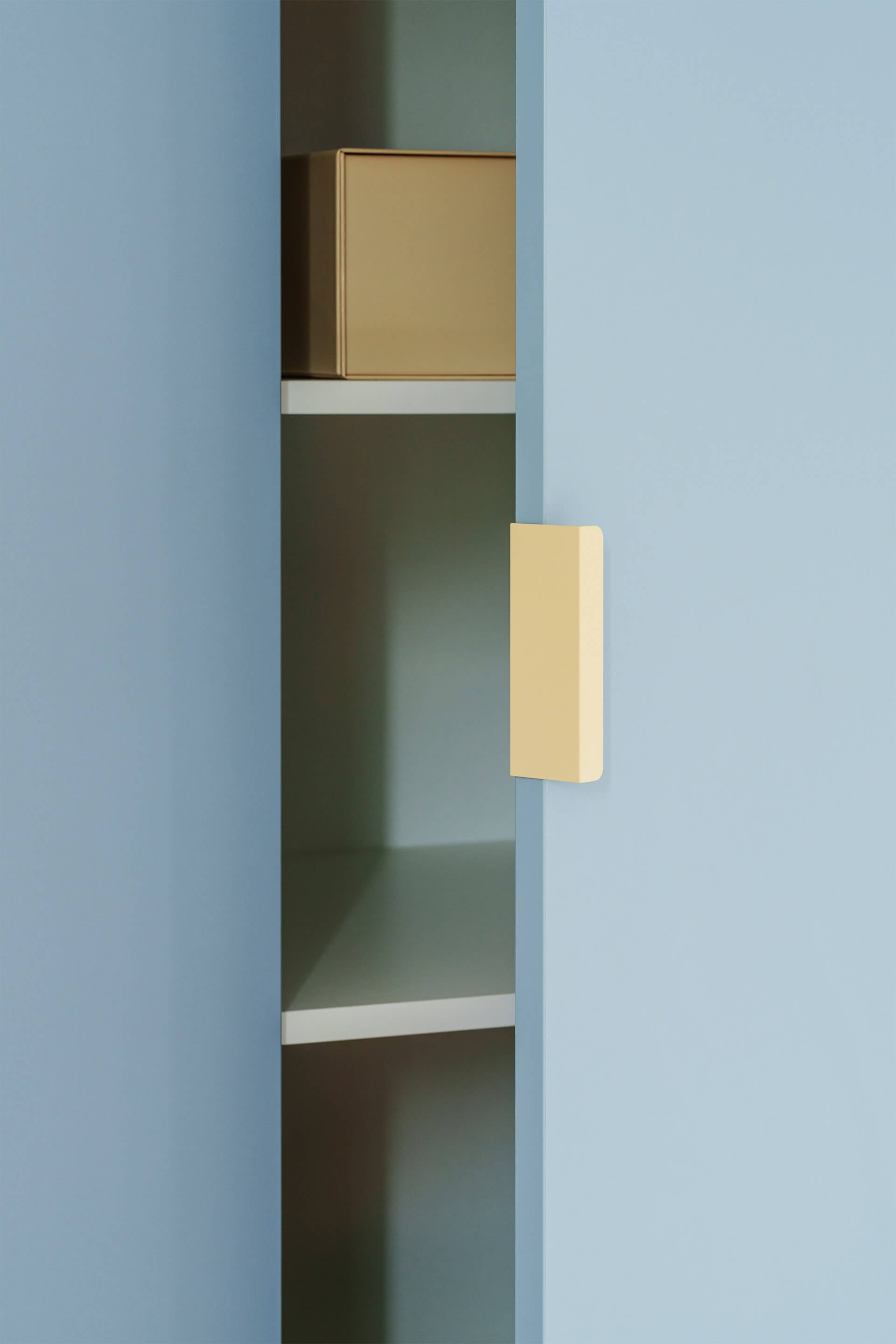 Detail shot van de Tonton creme handgrepen die werden gemonteerd op een Silver Blue op maat gemaakte kledingkast. De deur van de kast staat half-open.