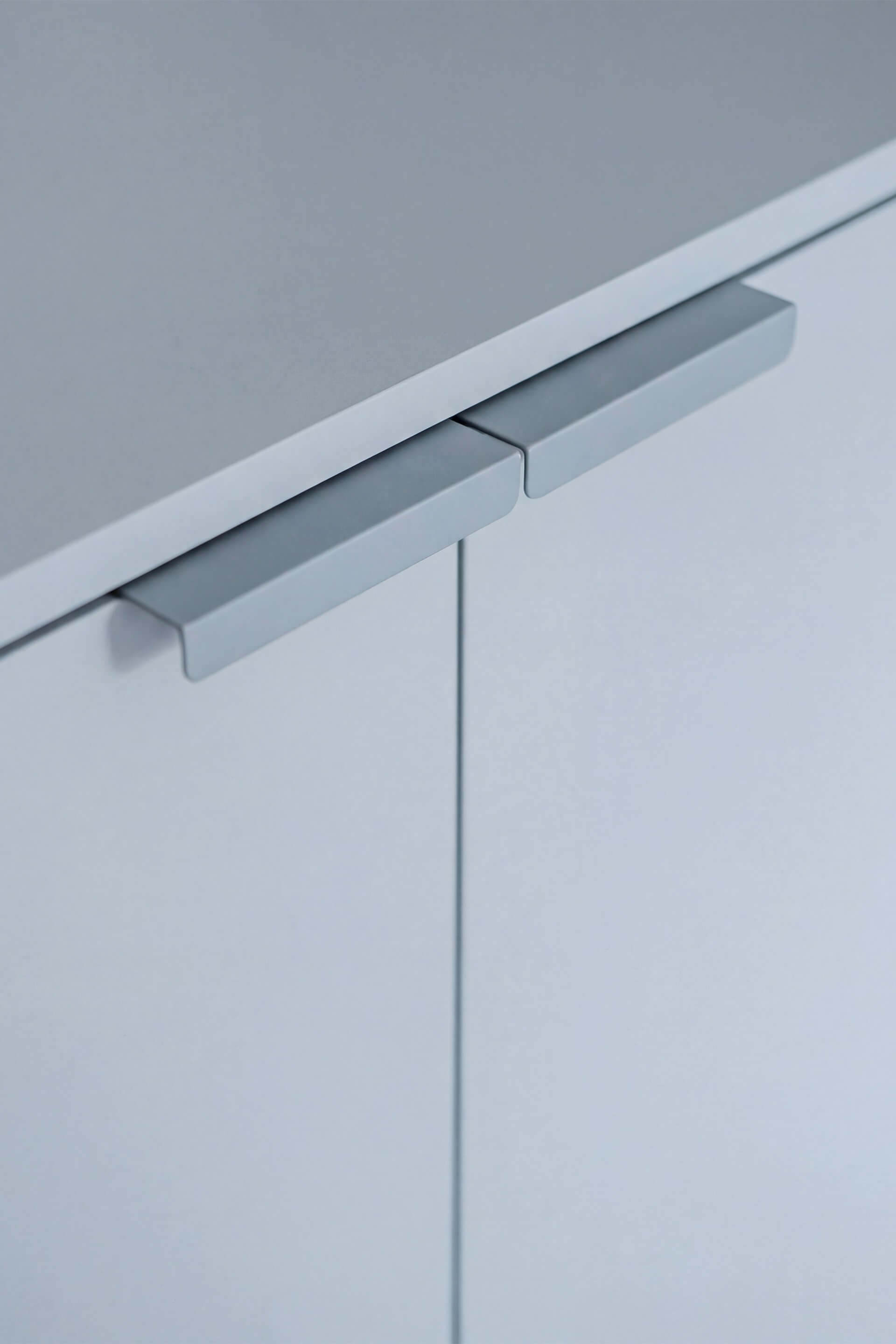 Two blue Tonton handles side by side, horizontal, on a Silver Blue chest of drawers. 