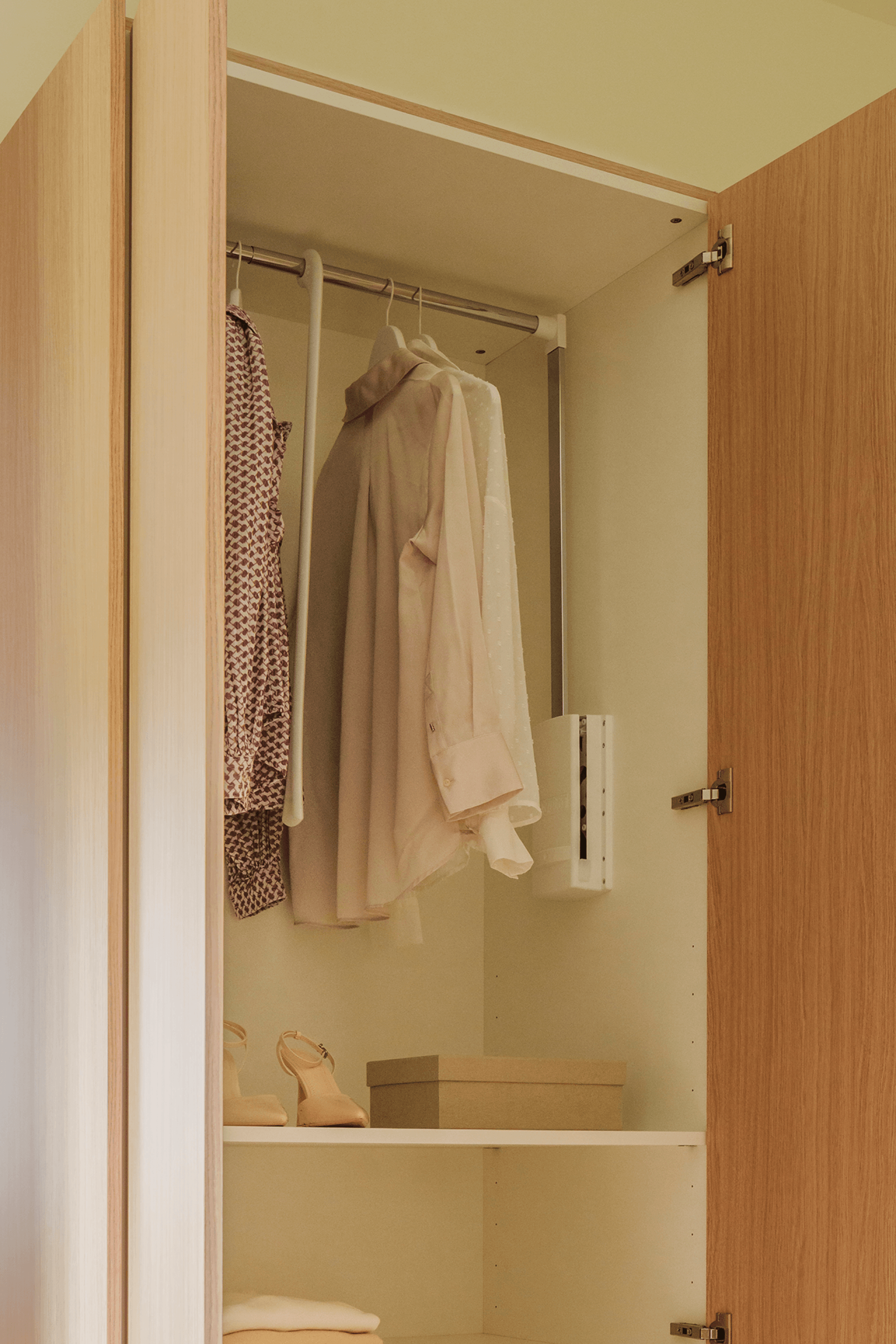 Atmospheric image of a white garment lift with clothes for your custom-made wardrobes. Available in the Maatkasten Online boutique.