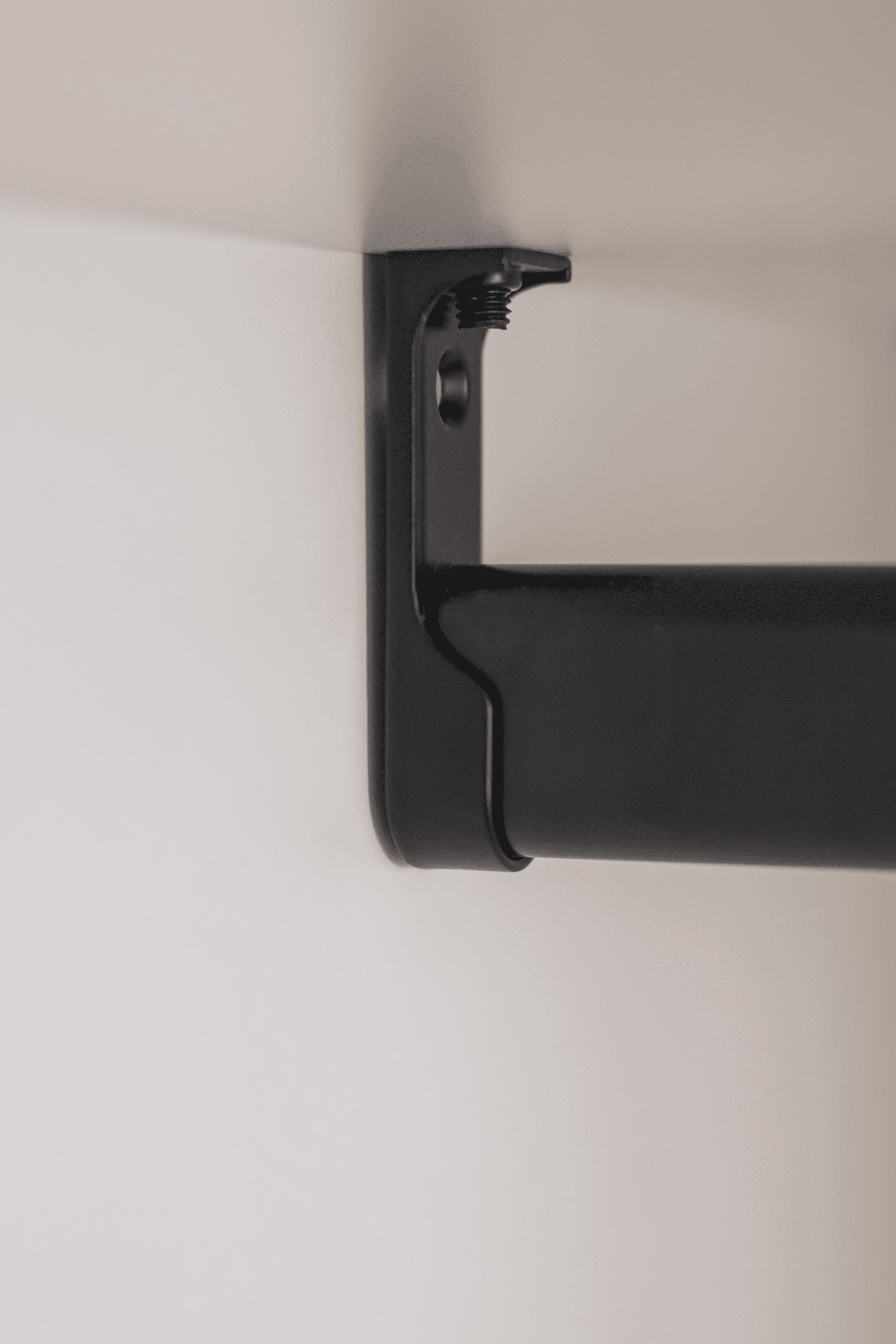 Detail shot of a black clothes rail mounted in a white custom wardrobe. Perfect 90° angle.